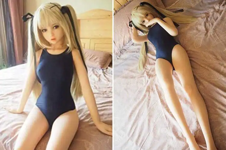Realistic sex doll with blonde hair in a blue outfit, posed on a bed.